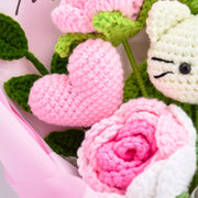 Makroansicht eines rosa Häkelherzens und einer zweifarbigen Rose neben dem weißen HK-Motiv