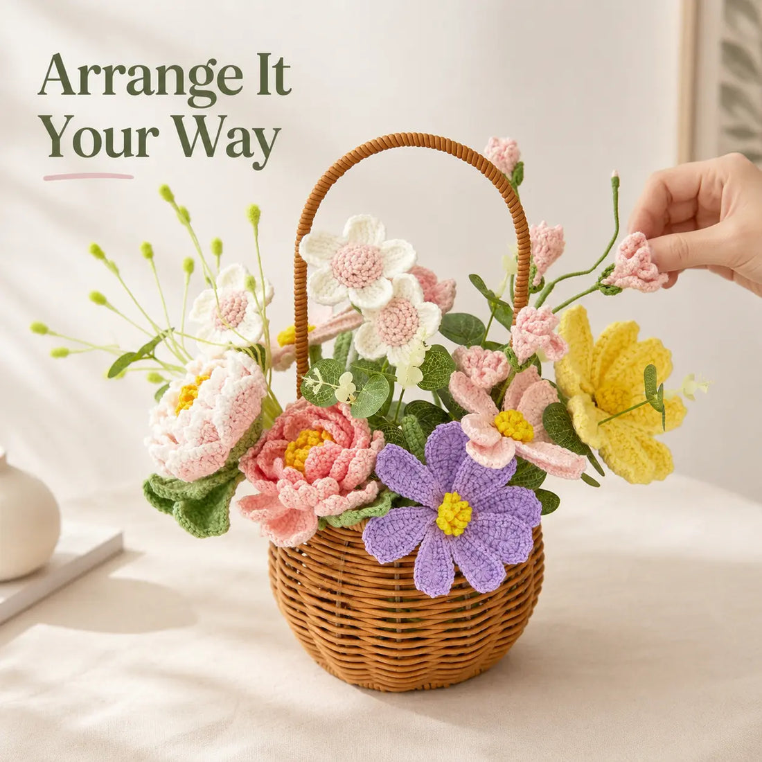 Arrange It Your Wayの文字と、丸型バスケットのピンクのかぎ針編み花茎を並べ替える手