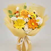 Vista frontal del ramo amarillo de ganchillo con girasol y abeja, flores naranjas, blancas y amarillas, y envoltorio amarillo en capas