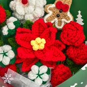 Dettaglio della stella di Natale rossa all’uncinetto con centro giallo, circondata da rose rosse e fiori di cotone bianchi