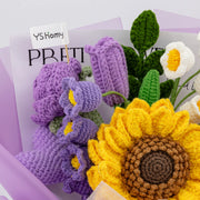 Purple crochet bouquet displayed beside a gift card, showing large sunflower, purple tulip, rose, white flowers, and green leaves