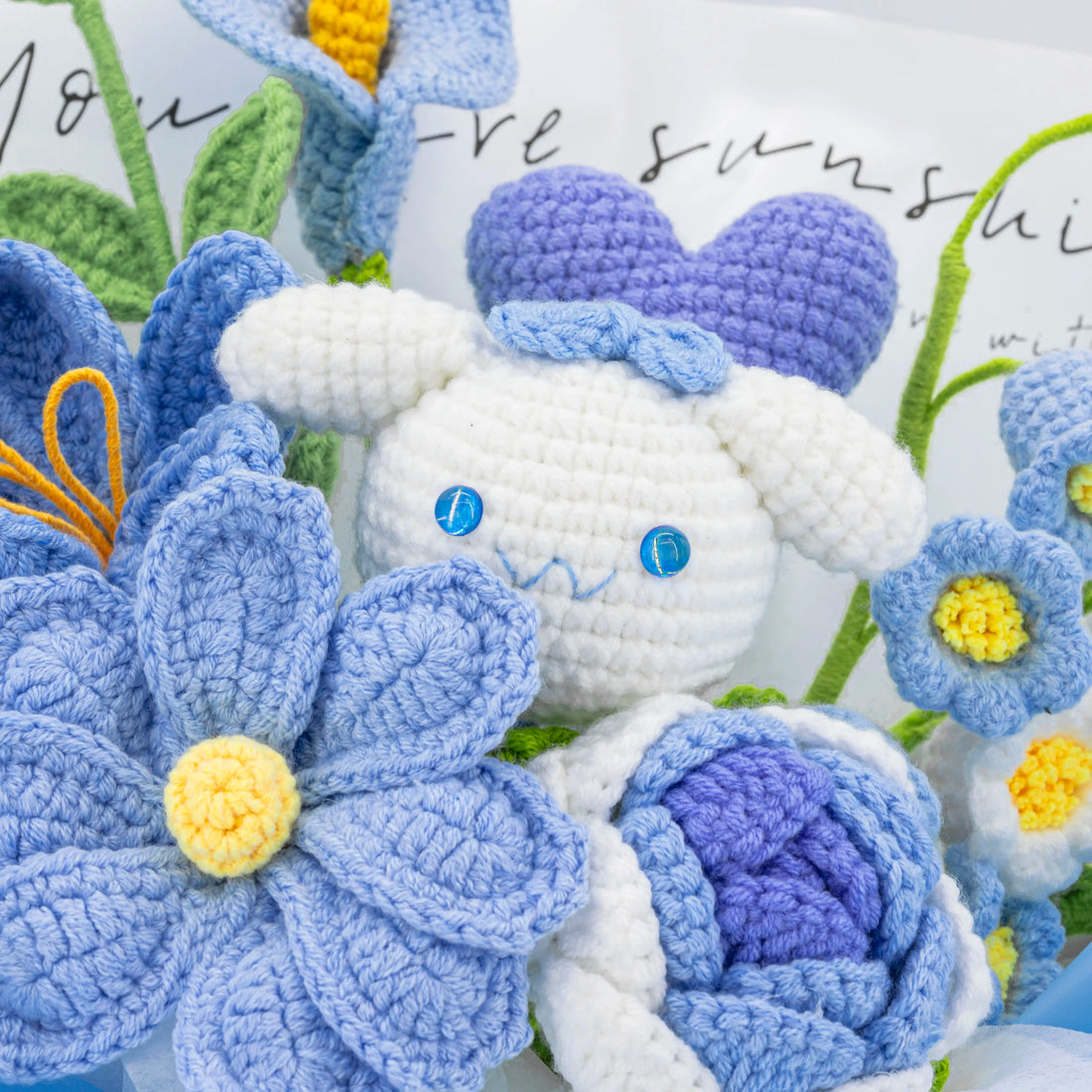 Detail der weiß-blauen CN-Figur neben einer blauen Blume und einem violetten Herz