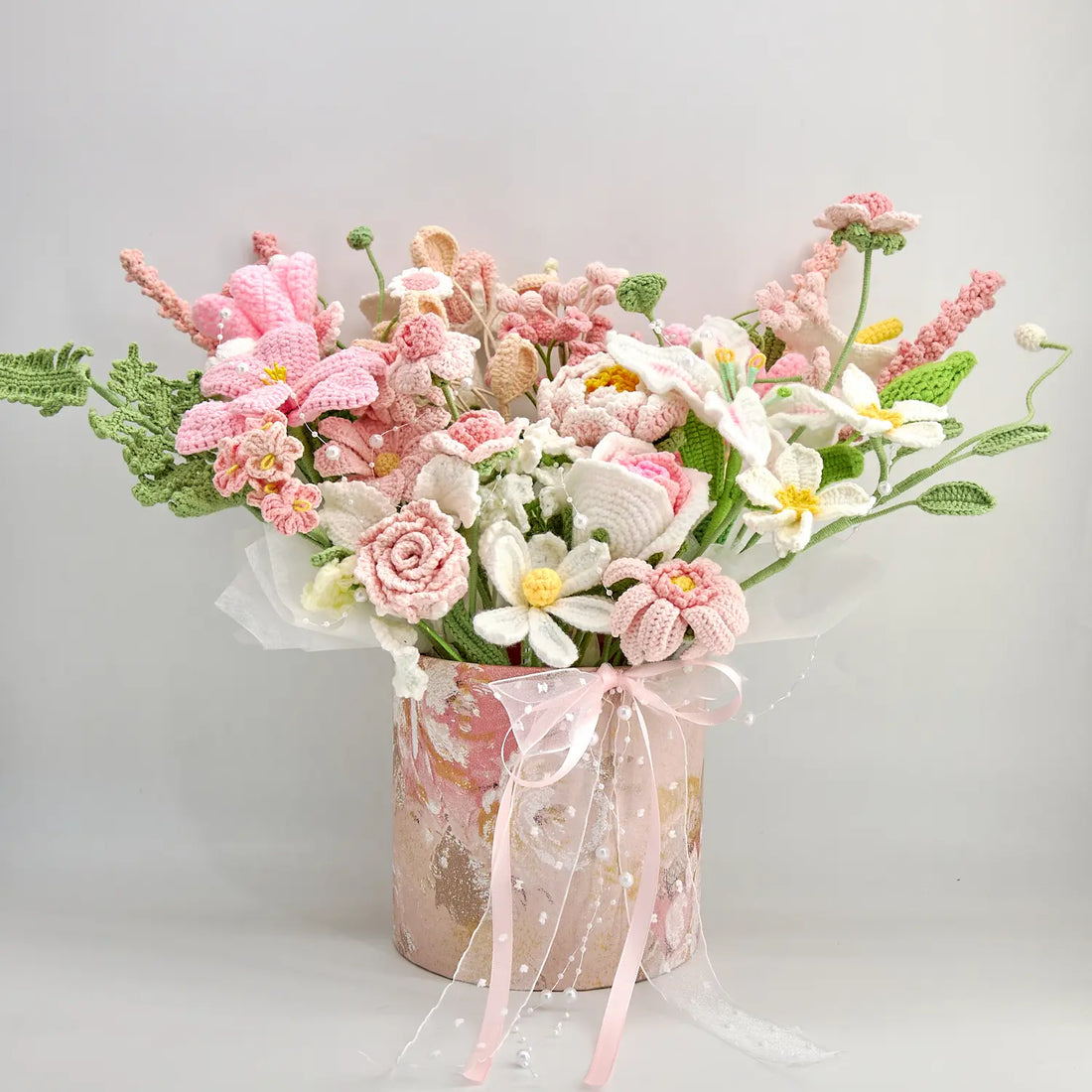 Full crochet gift-box bouquet with mixed pink and white blooms, green leaves, pink ribbon, and pearl-like details
