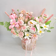 Front view of pink, white, and green crochet flower bouquet in a round pink gift box with ribbon and bead strands