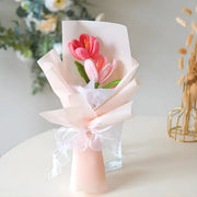 軽いと暗いピンクの2つのオープンチューリップのハンドヘルドかぎ針編みの花束