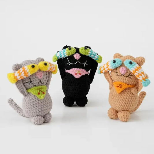 Crochet cat doll with a fish, standing on a wire-shaped tail