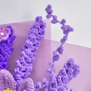 Primo piano di steli di lavanda all’uncinetto viola scuro e chiaro davanti all’incarto viola a strati
