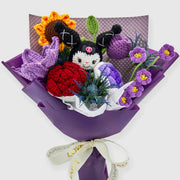 Front view of purple crochet KM bouquet with sunflower, red roses, purple flowers, blue greenery, and ribbon