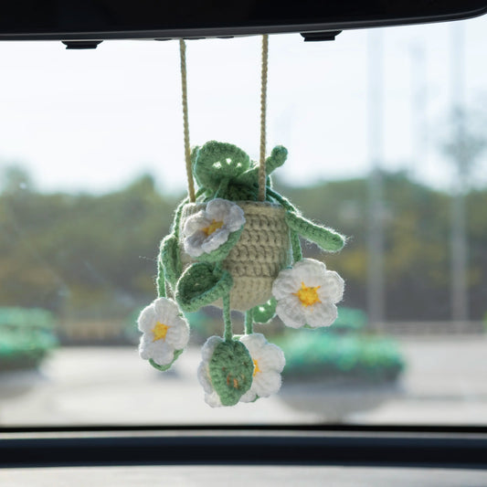Hollowed-out crochet car hanging with dark green leaves