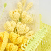 Close-up of pale yellow crochet buds, slender filler stems, pale green decorative leaf, and light yellow wrapping